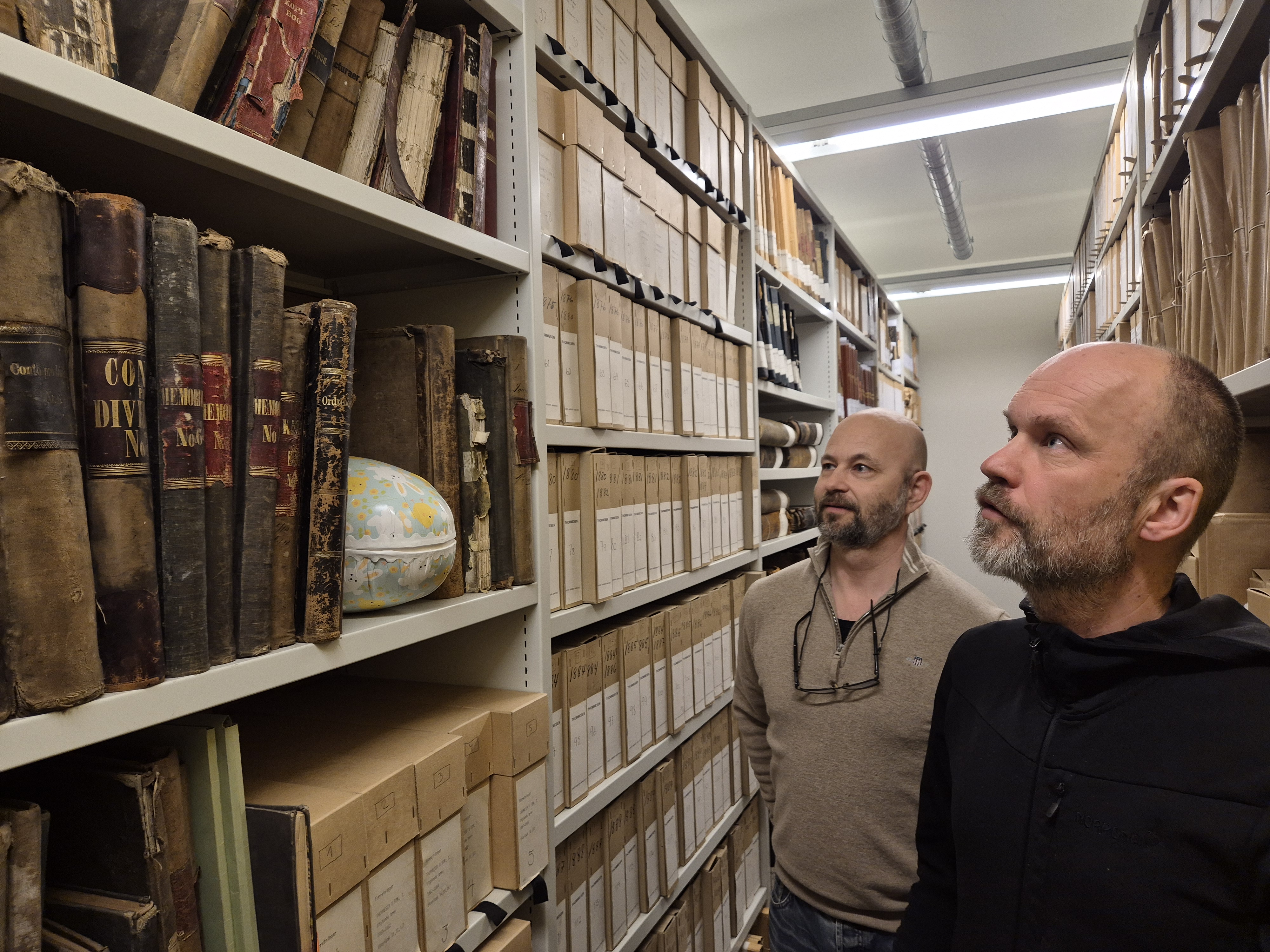 To menn og et påskeegg i akrivmagasin. 