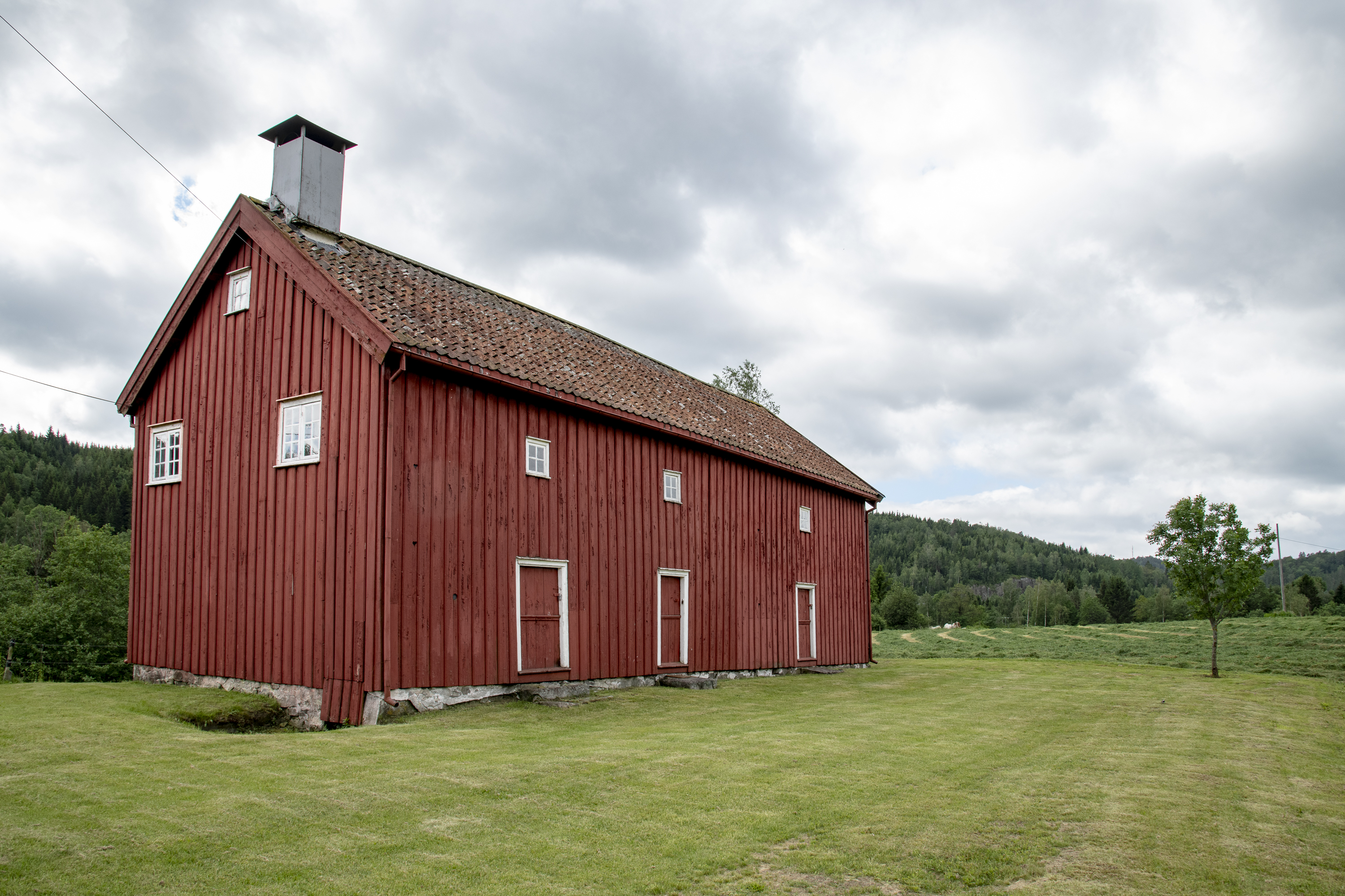 Bildet viser gammel rødmalt trebygning. 